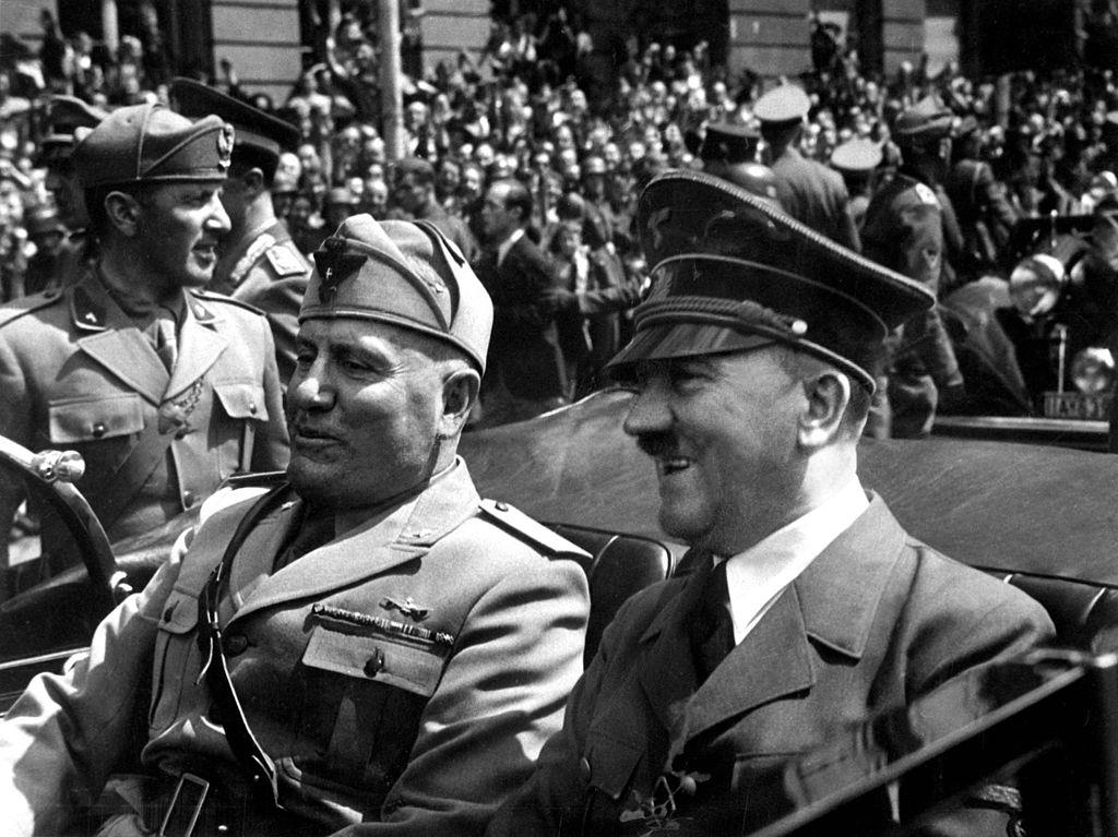 Hitler e Mussolini, em 1940. Dois homens desfilando para uma multidão sentados em um carro aberto
