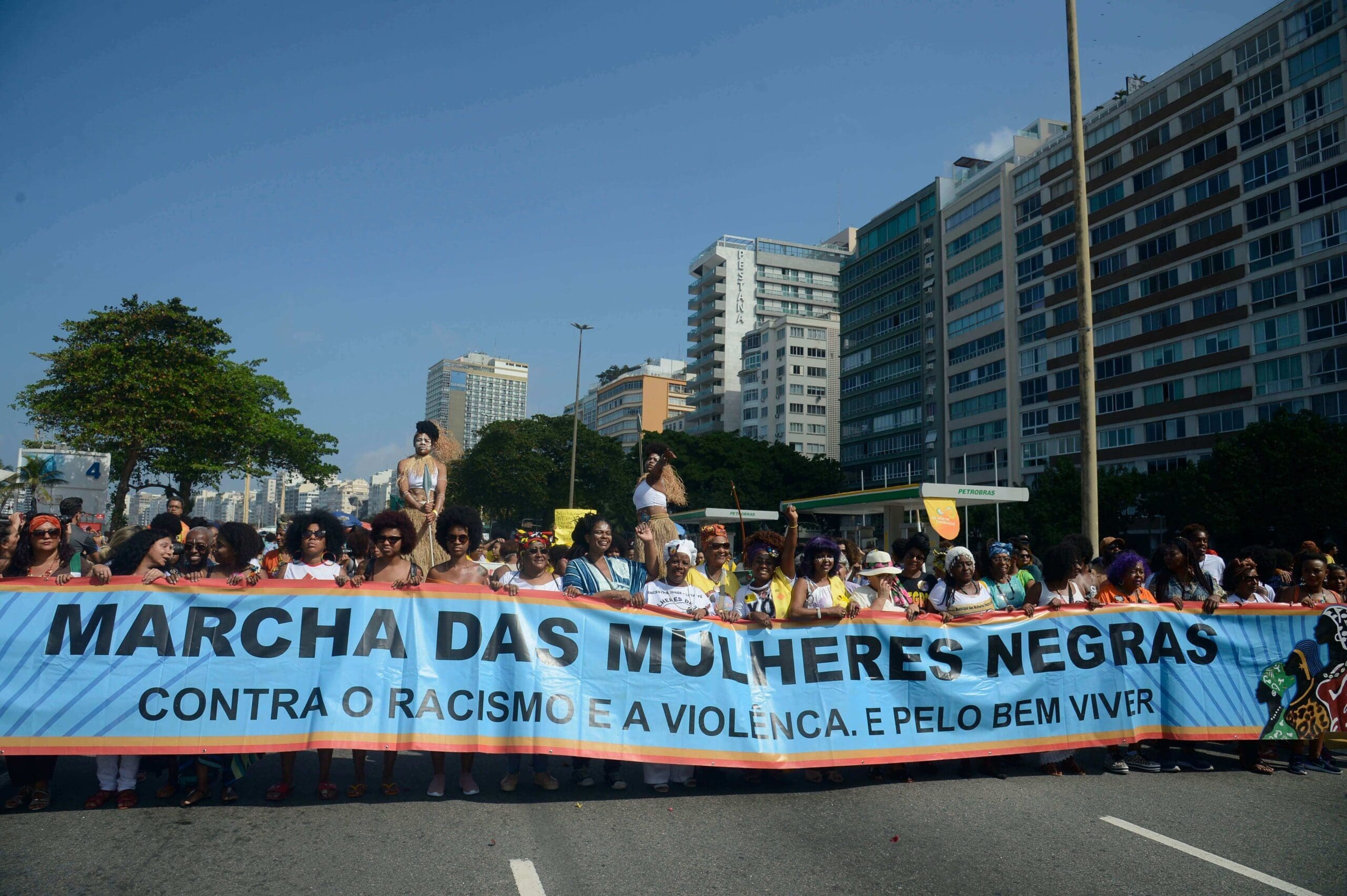 mulheres segurando faixa com a frase 'marcha das mulheres negras contra o racismo e a violência'. Conteúso sobre representatividade.