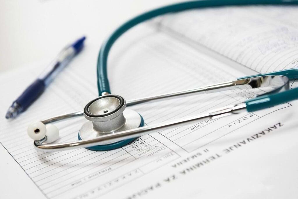 Imagem de um estetoscópio em cima de uma ficha médica. Apresentando o ODS 3, Saúde e bem-estar