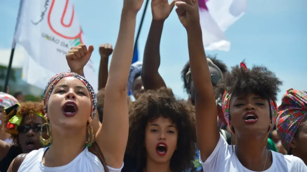 Imagem de três mulheres negras no que parece um protesto.