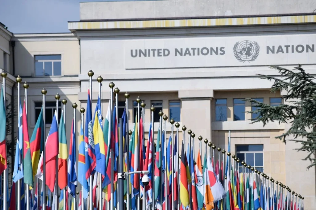 Imagem do prédio sede da ONU em Genebra, com bandeiras de vários países, simbolizando a importância das parcerias internacionais para alcançar as metas dos ODS.