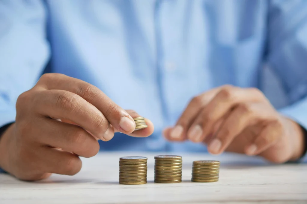Mãos empilhando moedas. Texto: O que é austeridade fiscal?