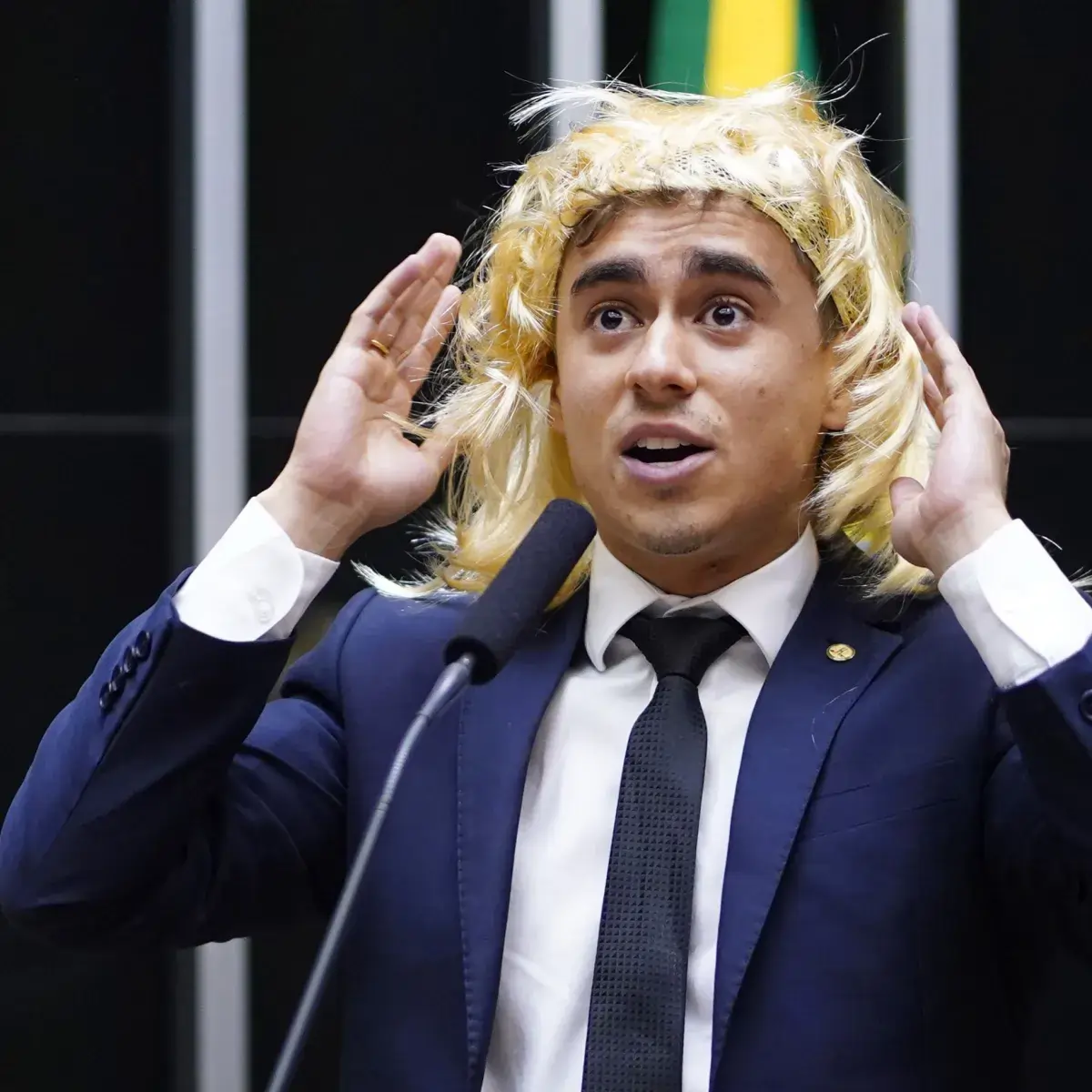 Imagem de Nikolas Ferreira usando peruca durante sessão na Câmara dos Deputados.