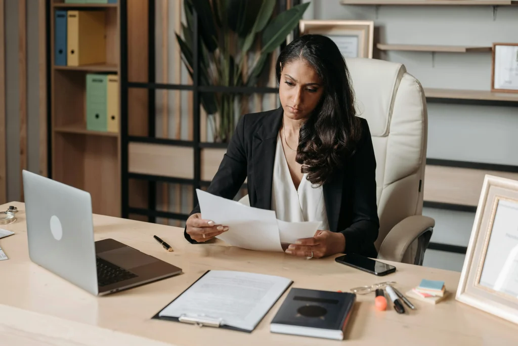 Mulher sentada à mesa, analisando papéis, representando a atuação estratégica no setor privado do Direito.