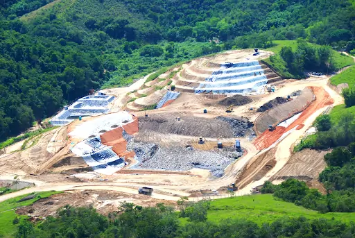 Vista aérea de um terreno de aterro sanitário. Texto: Aterro sanitário, aterro controlado e lixão: qual a diferença para descarte do lixo?