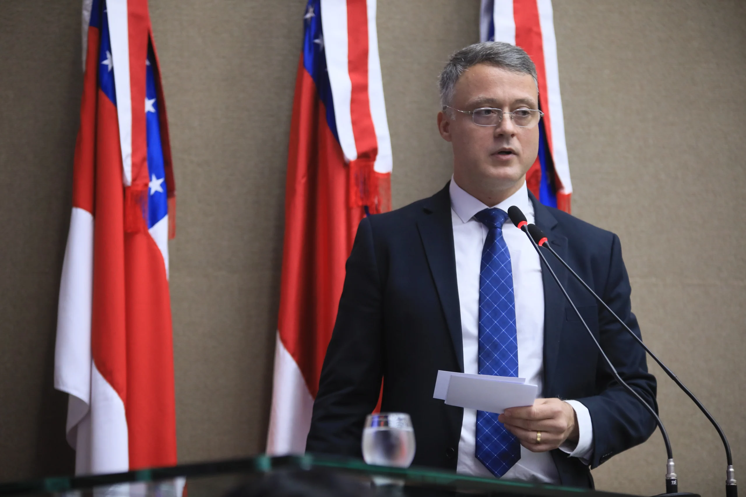 Homem branco de óculos, terno escuro e gravata azul, em pé, falando ao microfone durante sessão solene na Assembleia Legislativa do Amazonas.