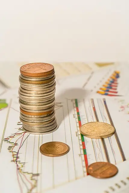 Moedas empilhadas sobre planilhas com dados econômicos.