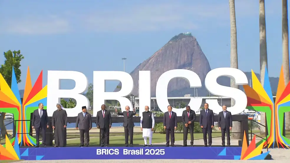 Líderes dos países do BRICS posam para foto oficial durante a cúpula realizada no Rio de Janeiro em 2025, com as bandeiras dos países-membros ao fundo.