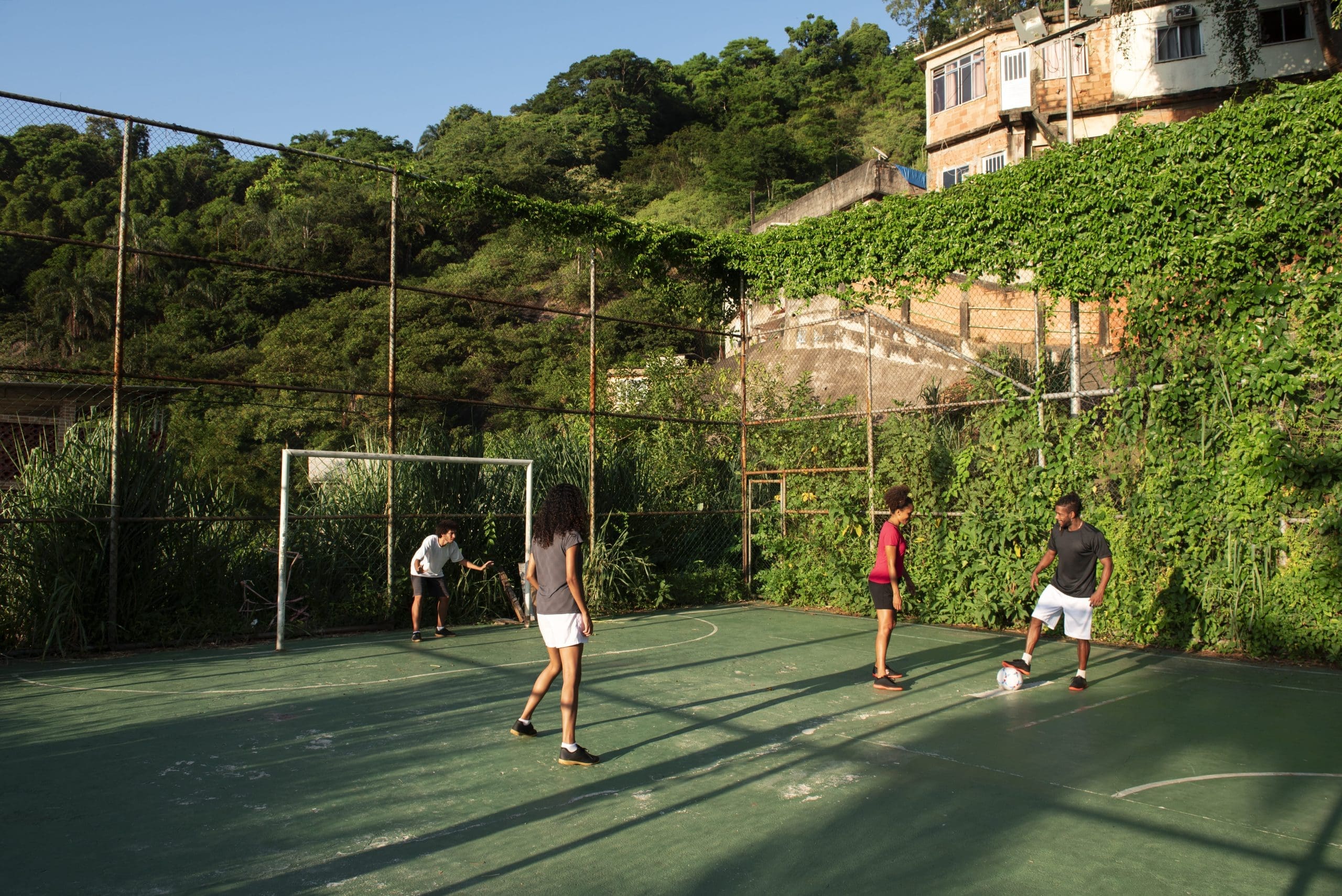 Grupo de pessoas joga futebol em uma quadra.